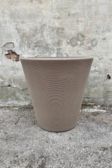 The 26" mocha Madison planter shown from the front against against a concrete wall. 