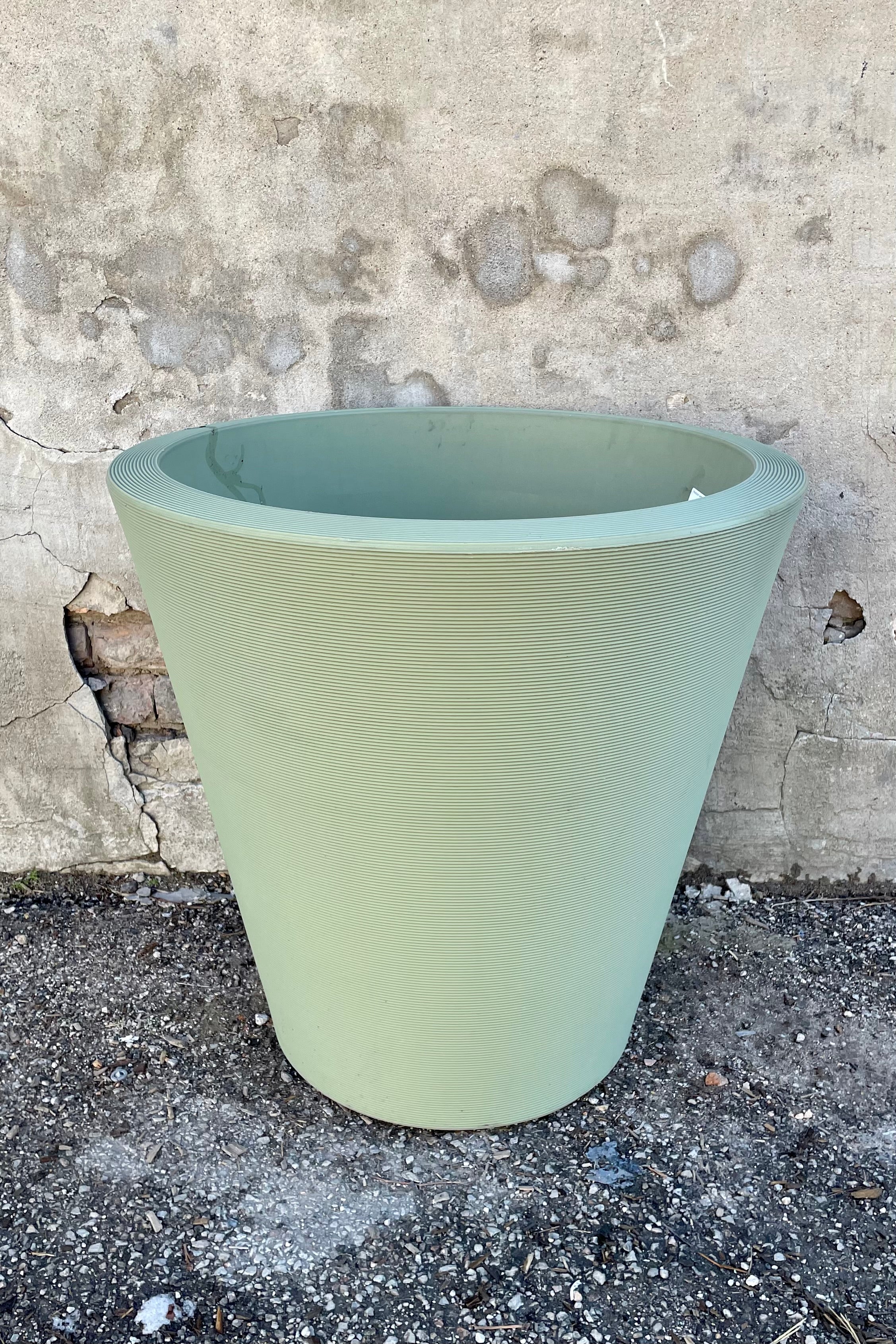 The lemongrass Madison 26" planter in front of a concrete wall. 