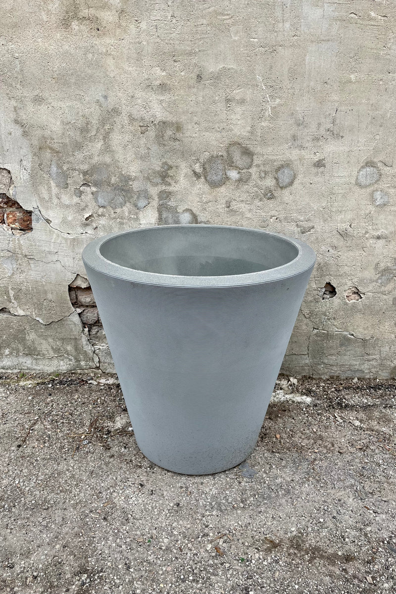 The Weathered grey Madison planter in a 26" diameter against a cement wall. 