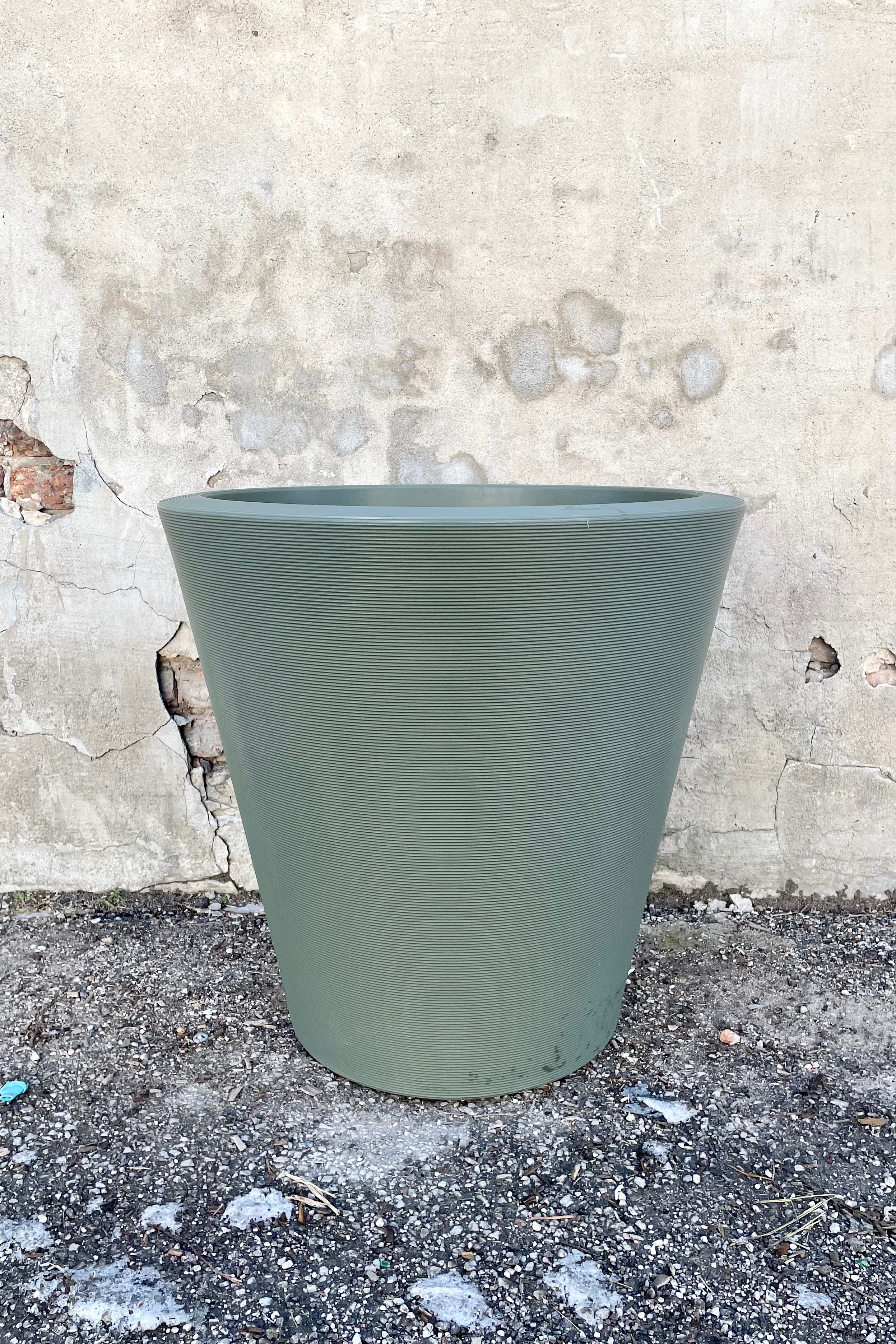 The olive 26" Madison planter against a concrete wall. 