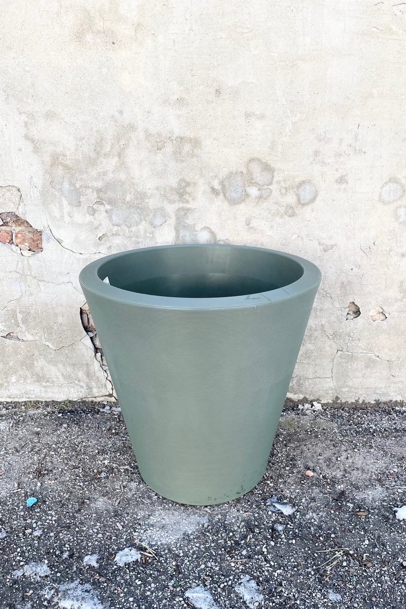 The olive 26" Madison planter against a concrete wall. 