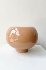 5" Nude colored round pot with a slight foot lift against a white wall.