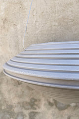 detail photo of the unplanted weathered stone Daniel hanging planter in front of a concrete wall. 