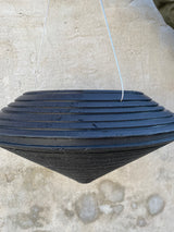 An empty Daniel hanging planter in caviar black against a concrete wall. 