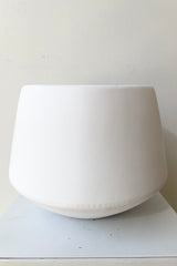 The large white valve pot viewed from the side against a white wall at Sprout Home.
