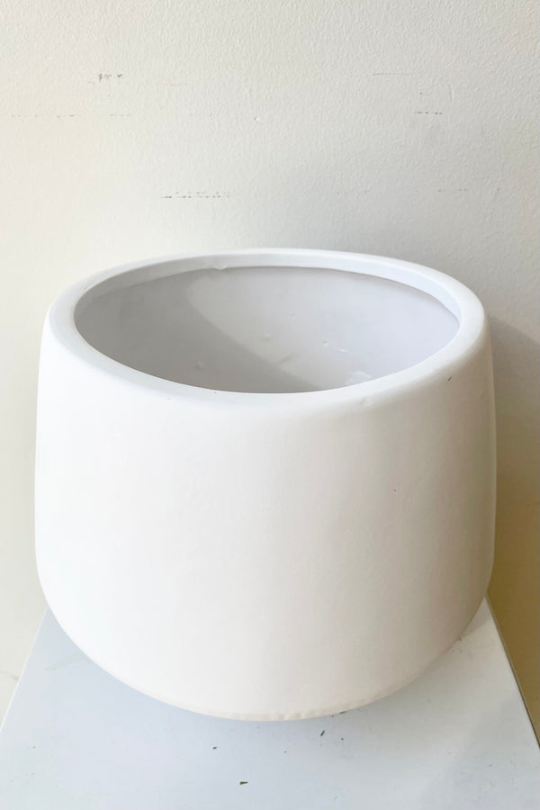 The large white valve pot viewed from the side and top against a white wall at Sprout Home.