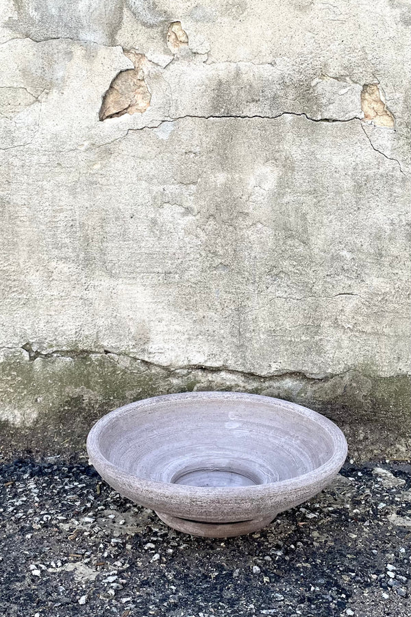 A frontal view of Ada Clay Bowl & Saucer grey 30cm against concrete backdrop