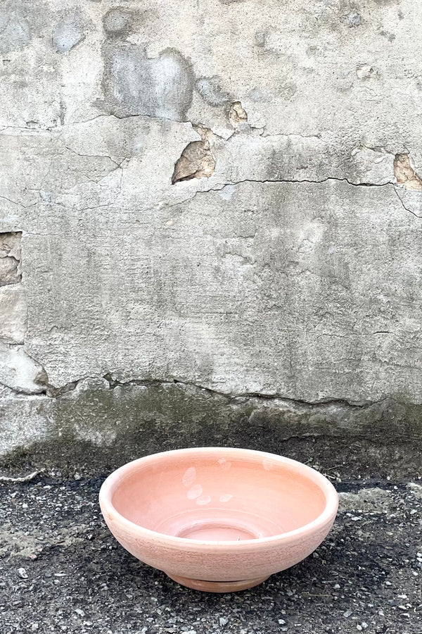 A frontal view of Ada Clay Bowl & Saucer rosa 30cm against concrete backdrop