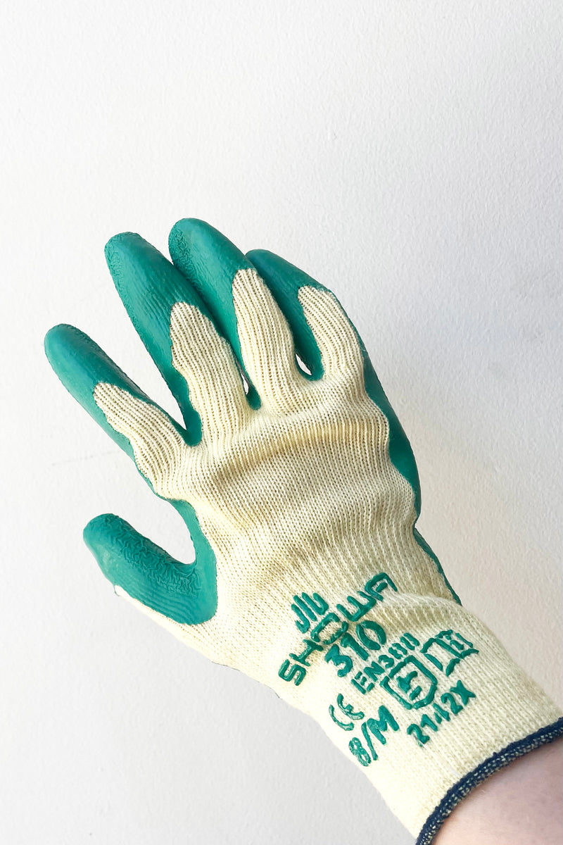A hand dons the Atlas Super Grip Gloves Medium against white backdrop
