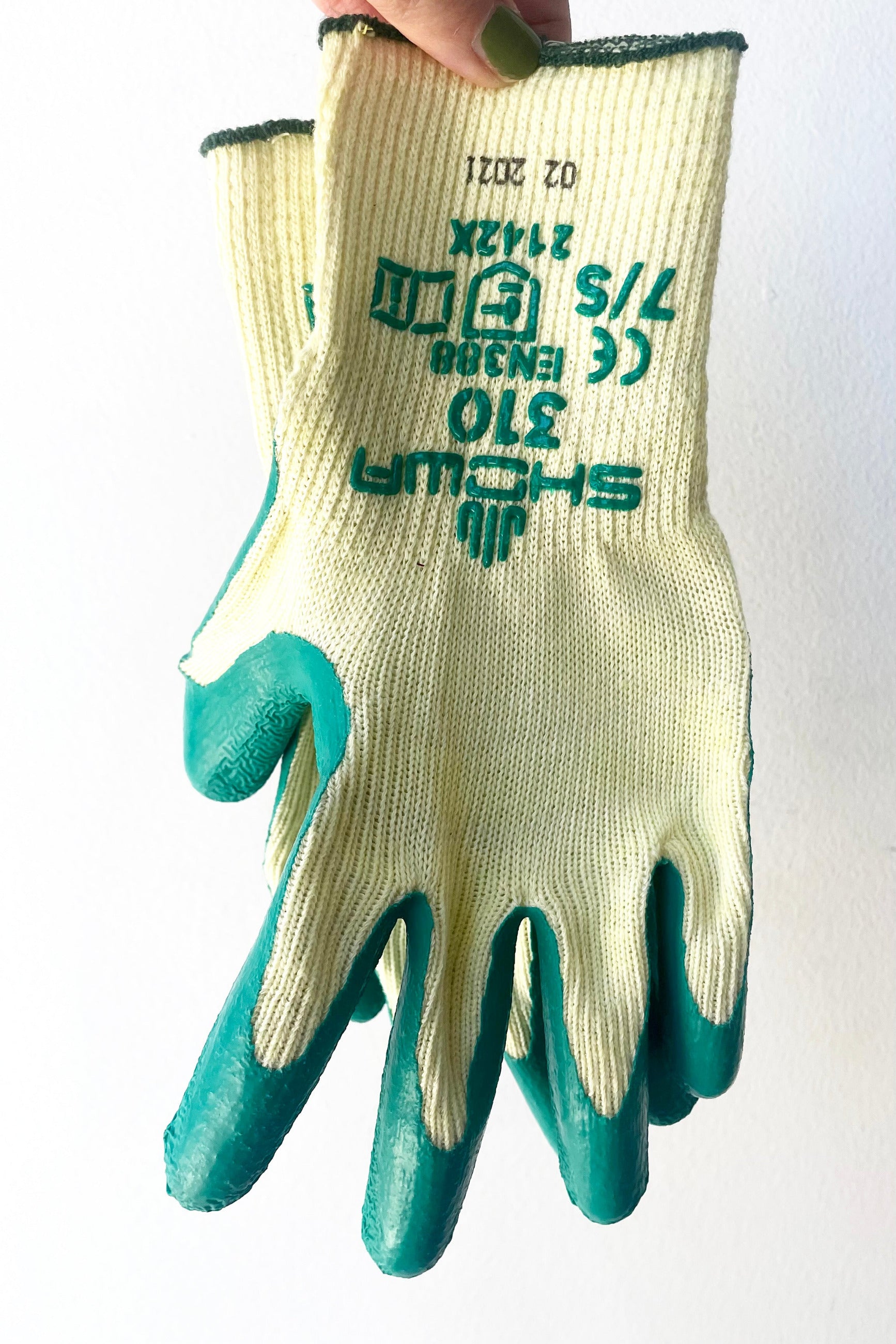 A hand holds the pair of Atlas Super Grip Gloves Small against white backdrop ©Sprout Home
