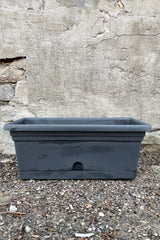 The 16" charcoal Emma rectangular hanging basket viewed from the front against a concrete wall. 