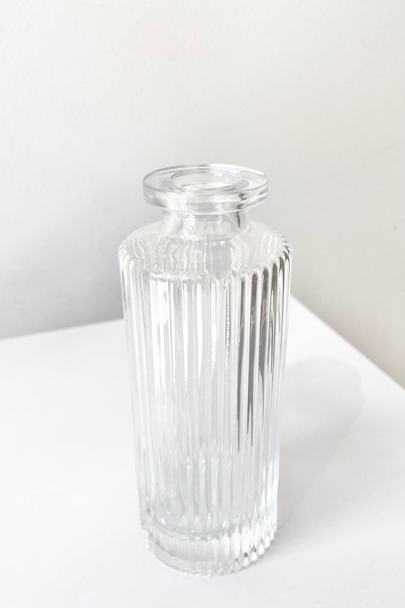 A slight overhead view of the Pleated Medicine Bud Vase in Clear against a white backdrop