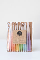 Ombre short assorted beeswax birthday party candles by knot and bow in front of white background