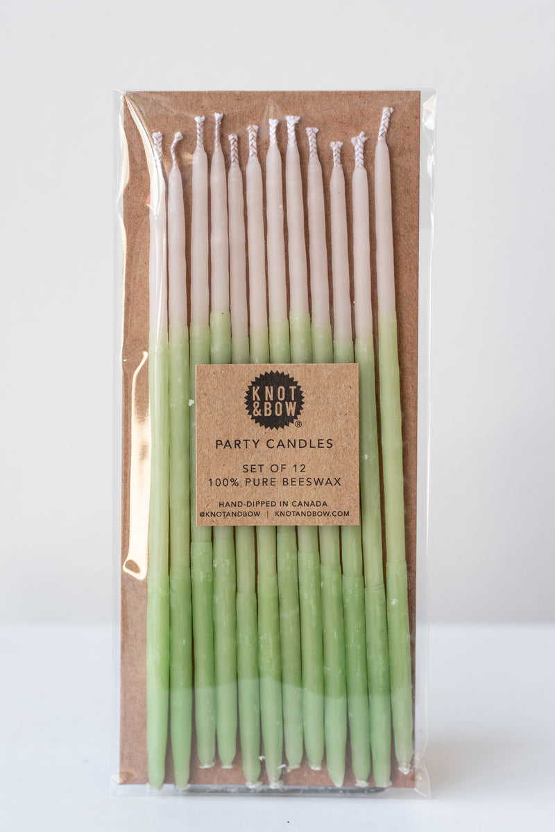Tall mint beeswax party birthday candles by knot and bow in front of white background