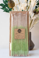Tall mint beeswax party birthday candles by knot and bow in front of green and white dried floral arrangement