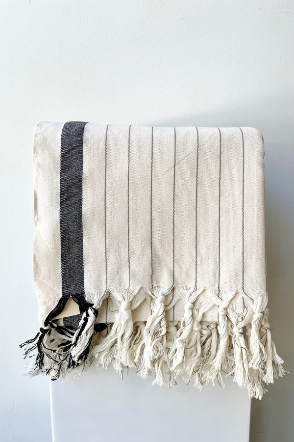 The Bodrum hammam towel folded against a white wall at Sprout Home. 