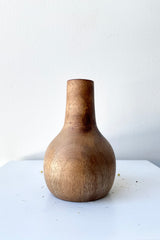 The Nina walnut wood vase large against a white wall at Sprout Home. 