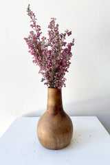 The Nina walnut wood vase large with dried floral against a white wall at Sprout Home. 