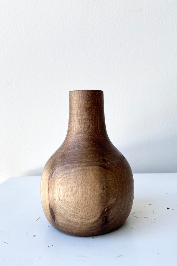 The Nina walnut wood vase against a white wall with dried floral at Sprout Home. 