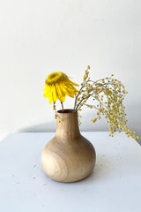 The walnut Nina wood vase against a white wall with dried floral at Sprout Home.