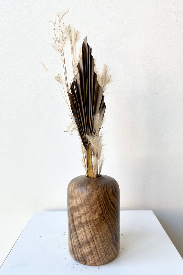 Patti walnut wood vase medium size with dried floral against a white wall at Sprout Home. 