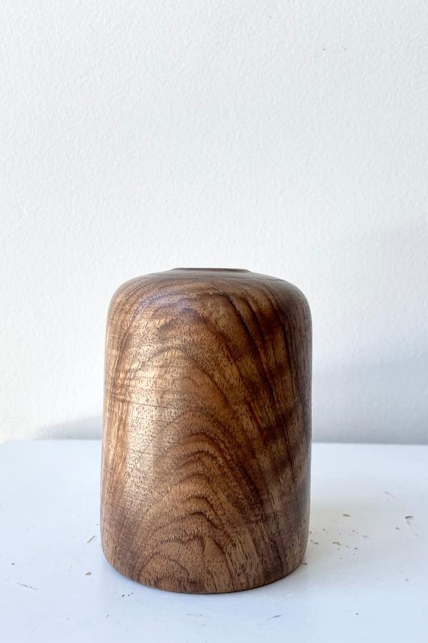 Patti Walnut wood vase against a white wall at Sprout Home.