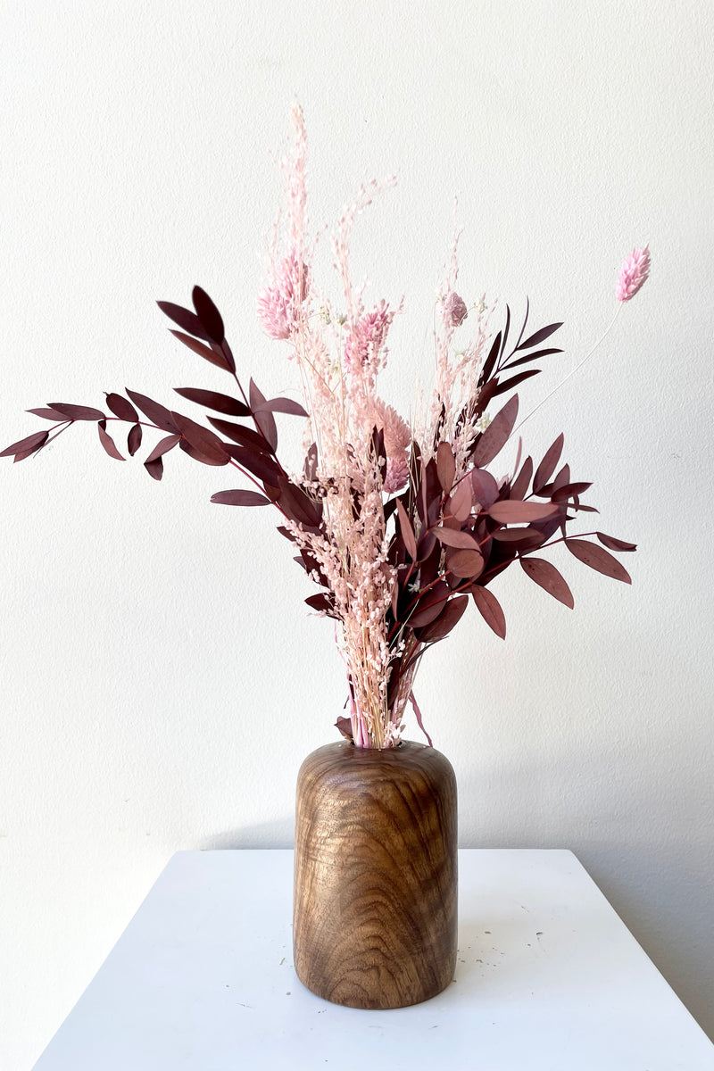 Patti Walnut wood vase with dried floral against a white wall at Sprout Home.