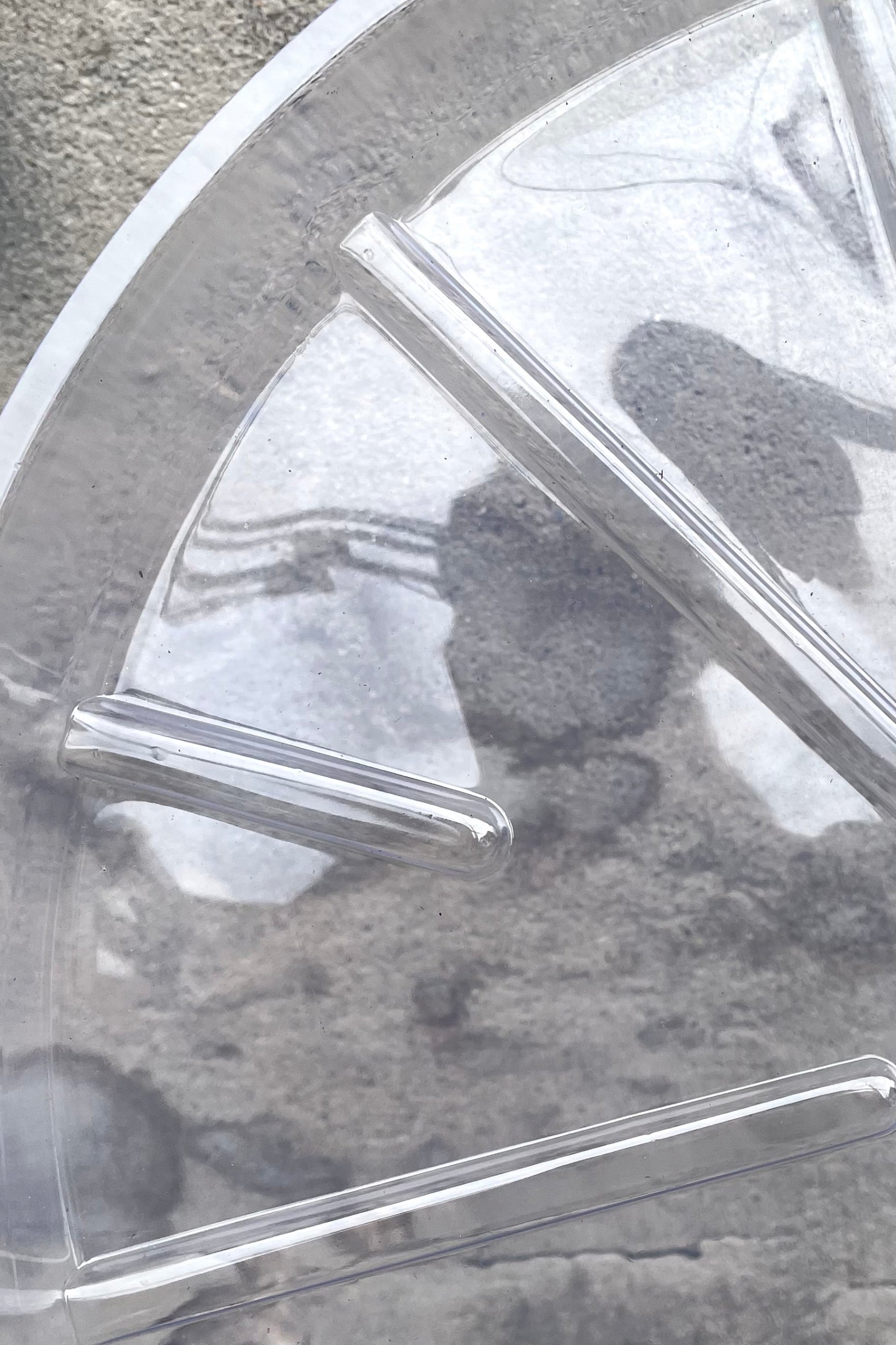 A detailed view of the interior ridges of Plastic saucer 16" against concrete backdrop  ©Sprout Home