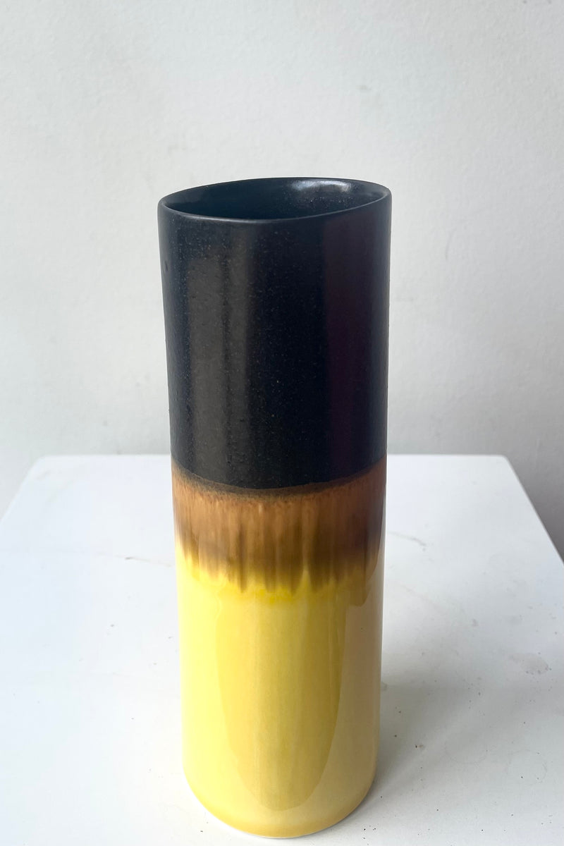 A slight overhead view of Cylinder Vase black & golden against white backdrop