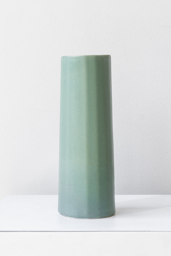 Bloom Vase in rosemary by The Bright Angle sits on a white surface in a white room.