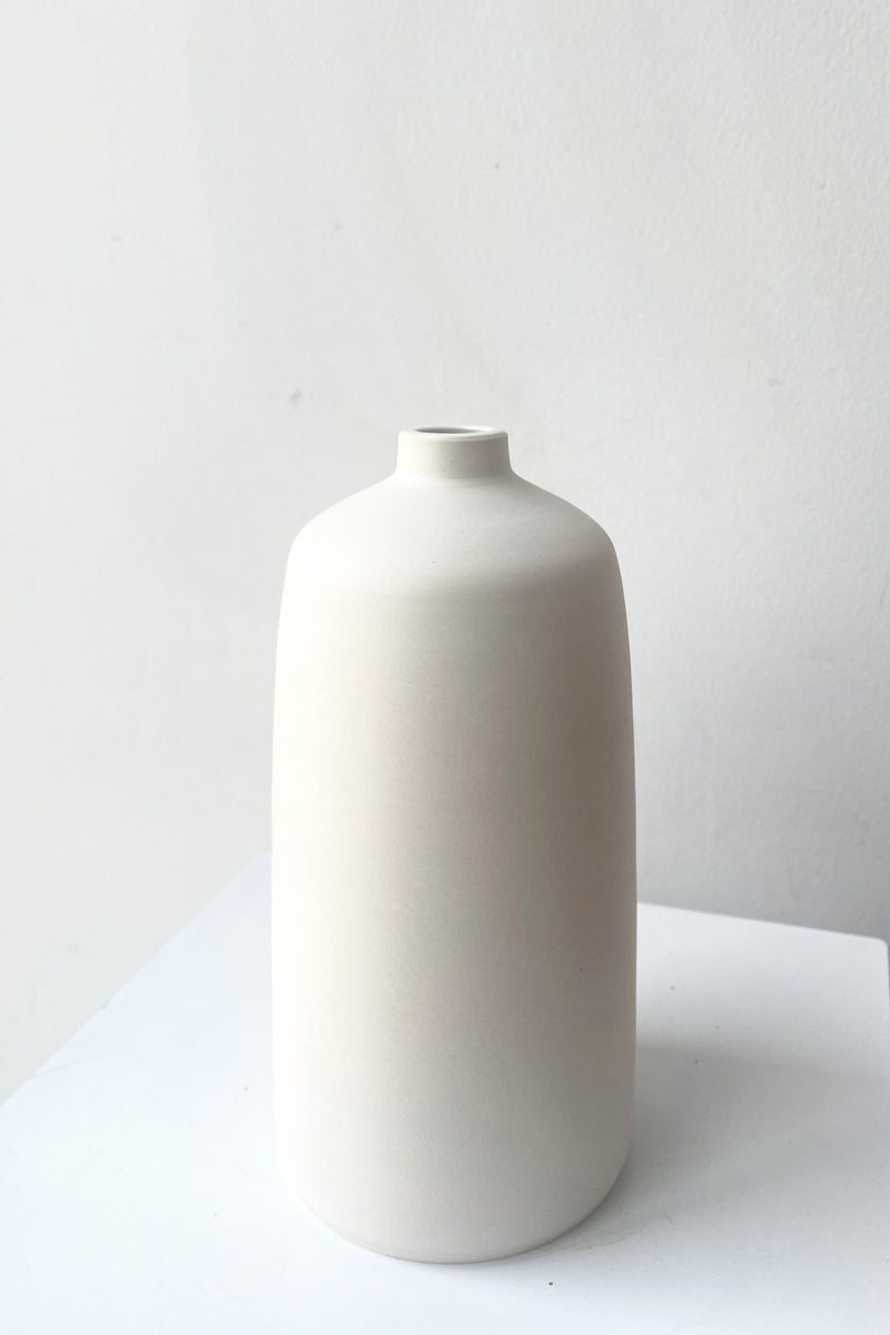 A slight side view of Bud Vase white medium against white backdrop