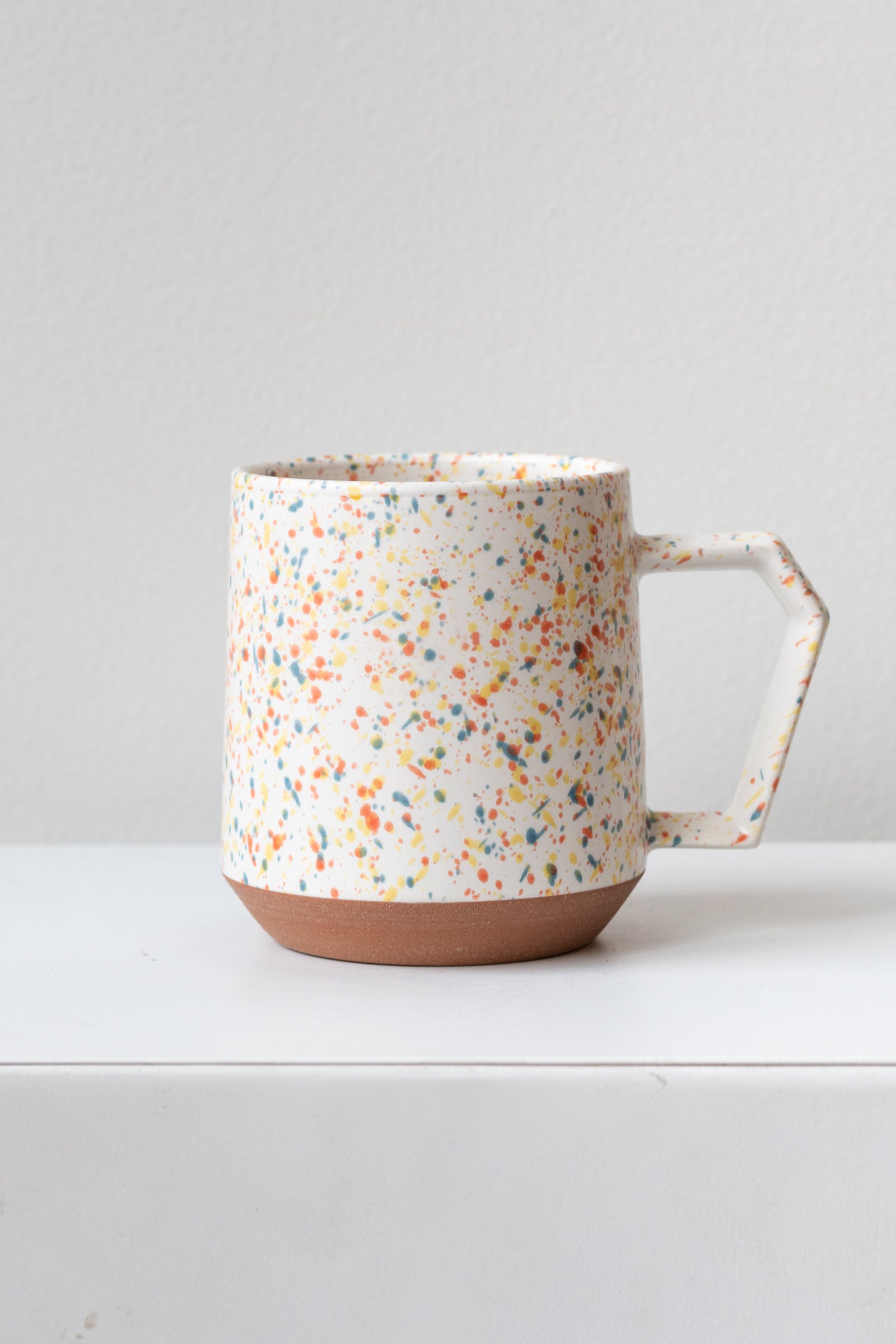 Color chips confetti mug by Miya Company Inc sits on a white surface in a white room