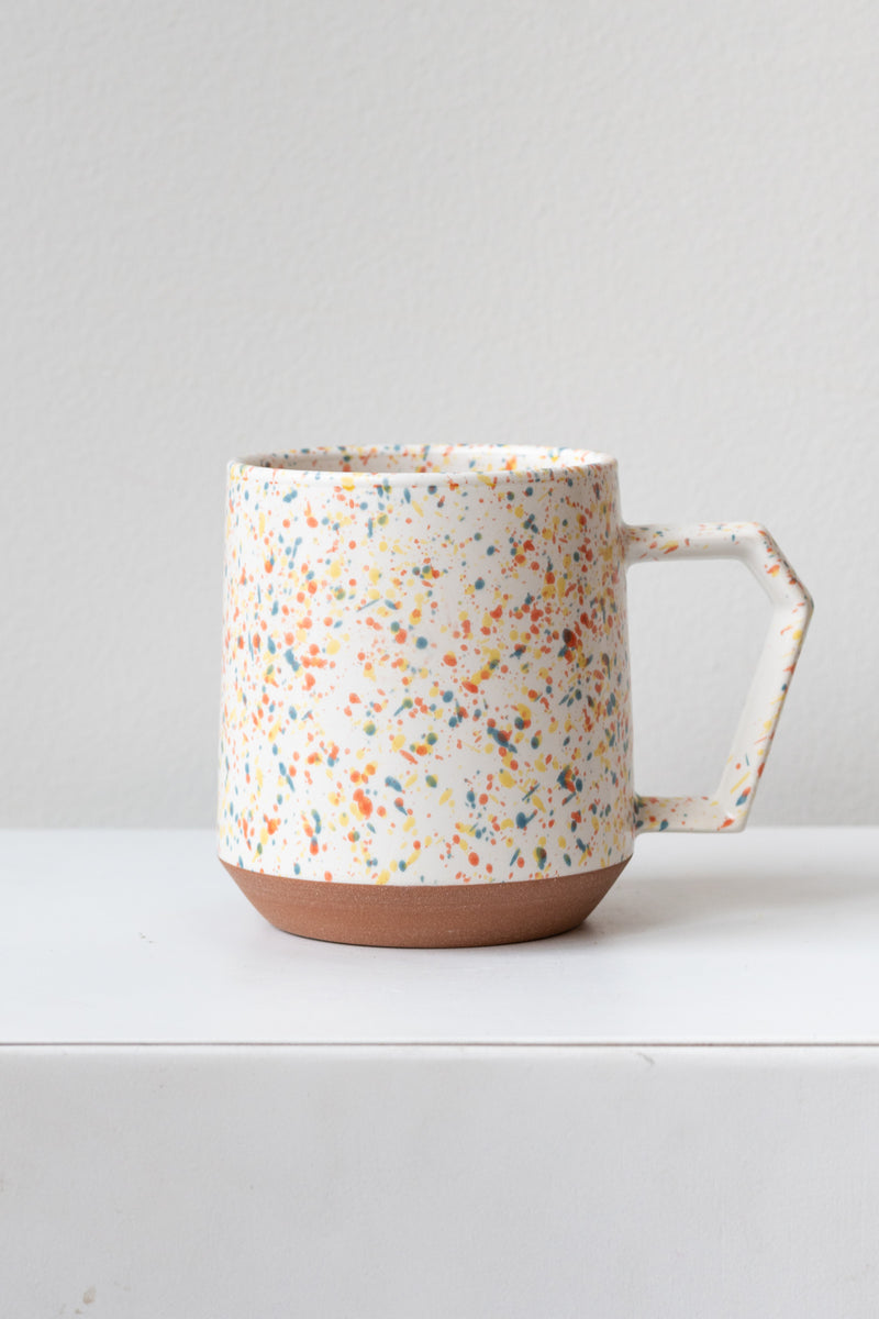 Color chips confetti mug by Miya Company Inc sits on a white surface in a white room