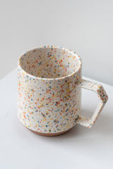 Color chips confetti mug by Miya Company Inc sits on a white surface in a white room