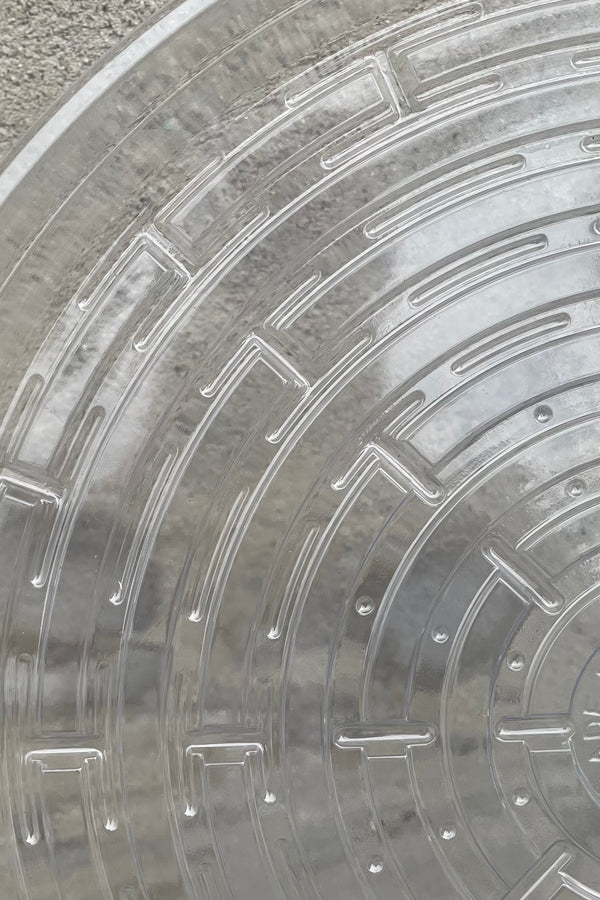 A detailed view of the interior ridges of Plastic saucer 14" against concrete backdrop