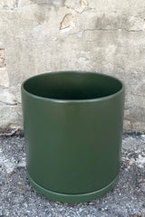 A slight over-the-lip view of the Solid Cylinder & Saucer Forest Green 12” against a concrete backdrop