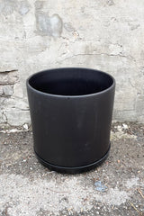 The 15" black solid cylinder and saucer against a concrete wall.  