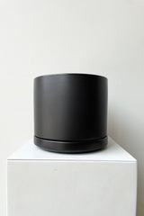 Solid Cylinder & Saucer black 6” against a white wall