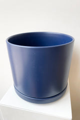 Detail of the top of Solid Cylinder & Saucer blue 8” against a white wall