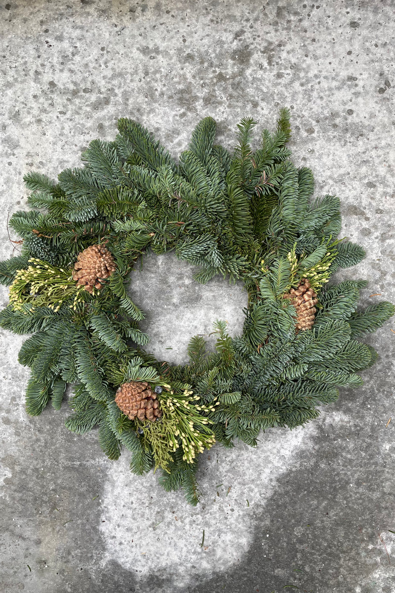 Small candle ring evergreen wreath with pine cone and cedar pieces.