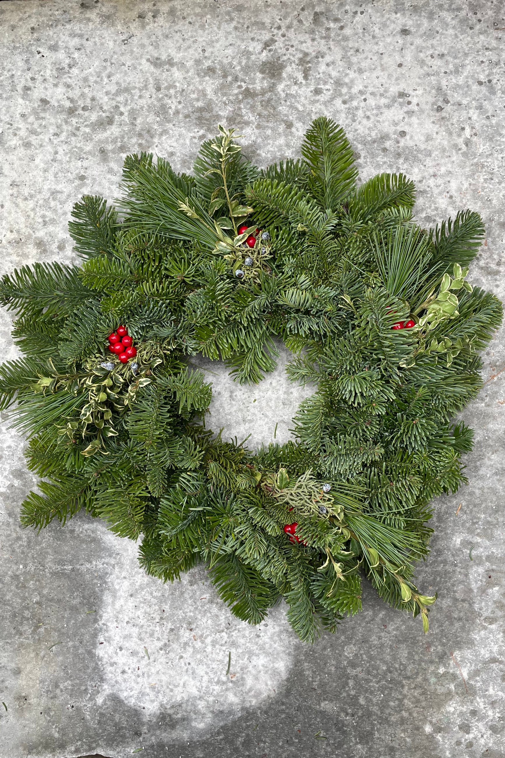 Simple evergreen wreath with pops of faux canella berry and pine. ©Sprout Home