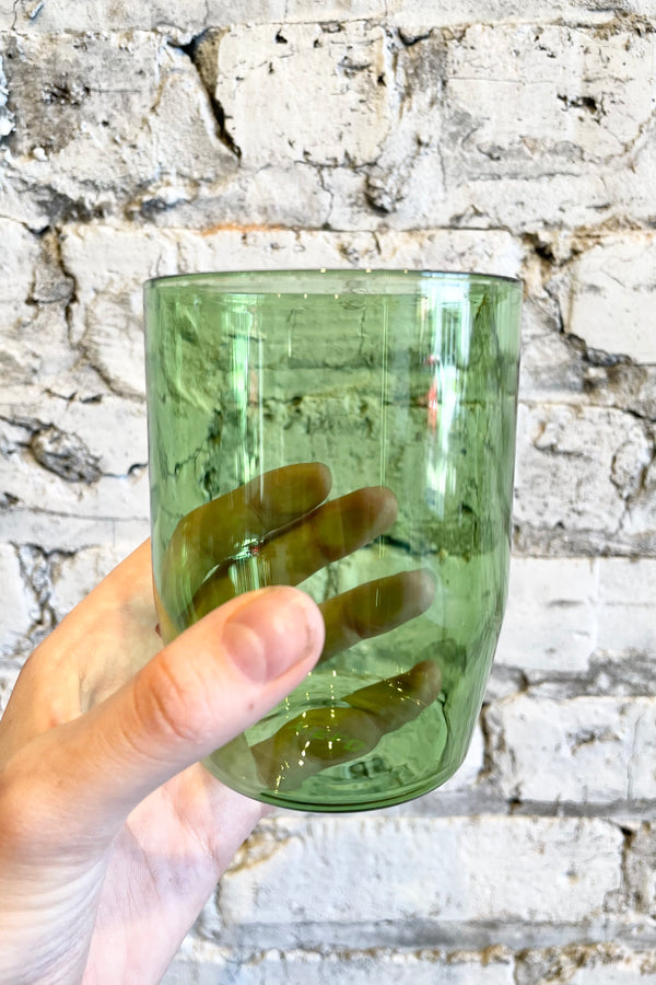 detail of Century Glasses green, 12oz - Set of 2 held against a grey brick  background 