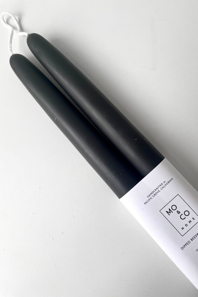 A close-up view of the Charcoal 14" Taper Candles, pair against a white backdrop