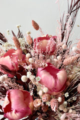 Sprout Home's Chocoberry Milkshake arrangement in detail showing the pink flowers and chocolate foliage against a white wall.