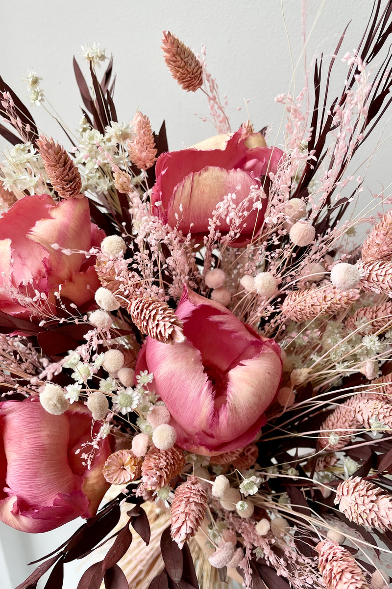 Sprout Home's Chocoberry Milkshake arrangement in detail showing the pink flowers and chocolate foliage against a white wall.