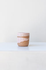 Pink Coastal Glaze Cup by Christina Kosinski sits on a white surface in a white room