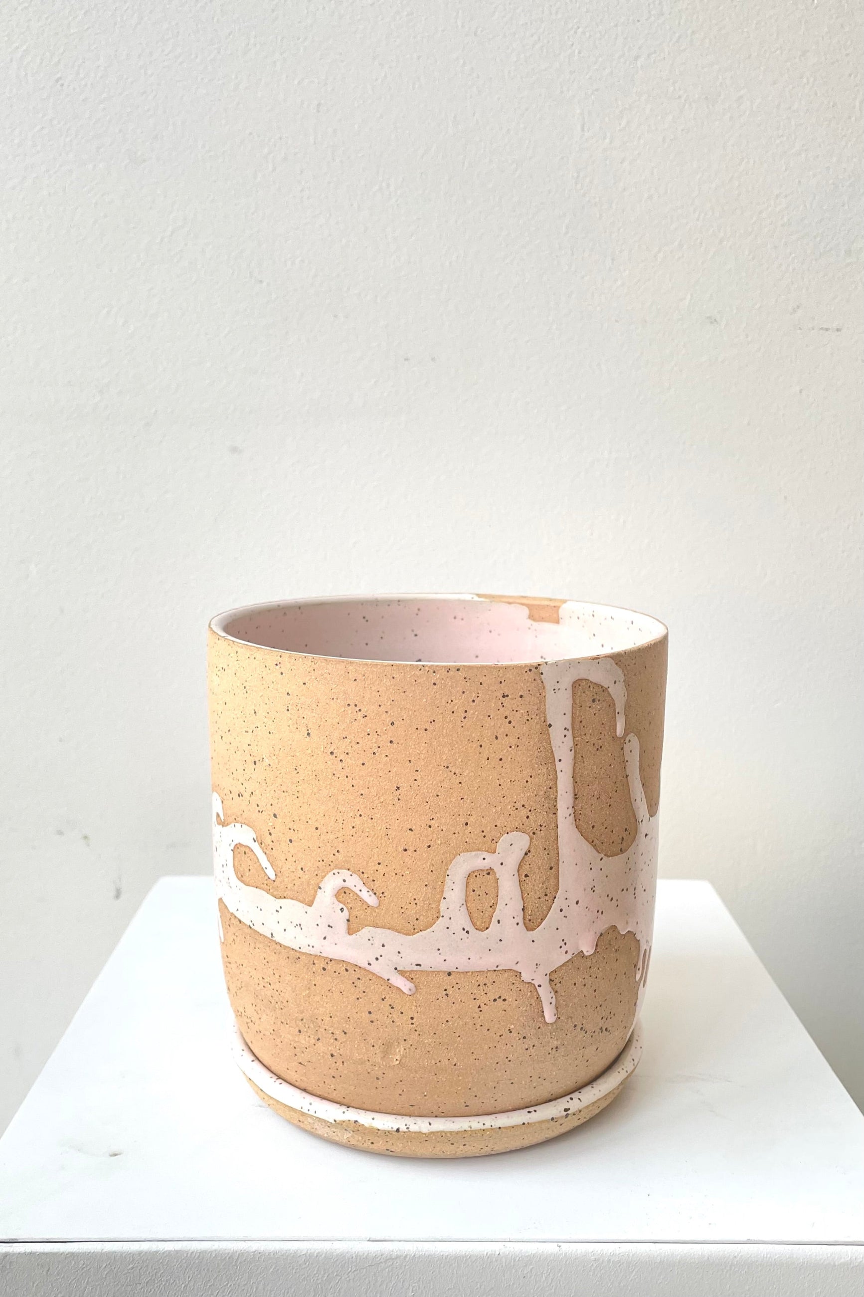 A slight over-the-lip view of the 4.5" cylinder pot and saucer in pink against a white backdrop ©Sprout Home