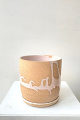 A slight over-the-lip view of the 4.5" cylinder pot and saucer in pink against a white backdrop