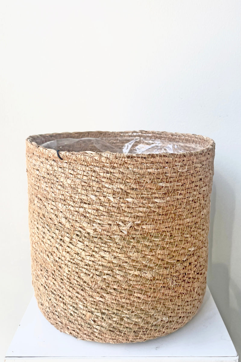 A slight over-the-lip view of Seagrass Basket with liner 7" against white backdrop