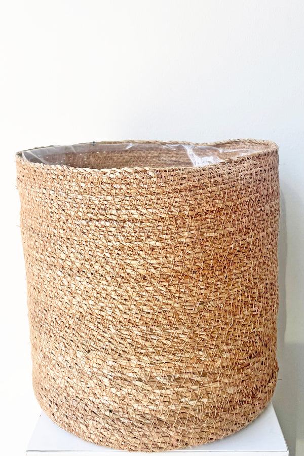 A slight over-the-lip view of Seagrass Basket with liner 11" against white backdrop